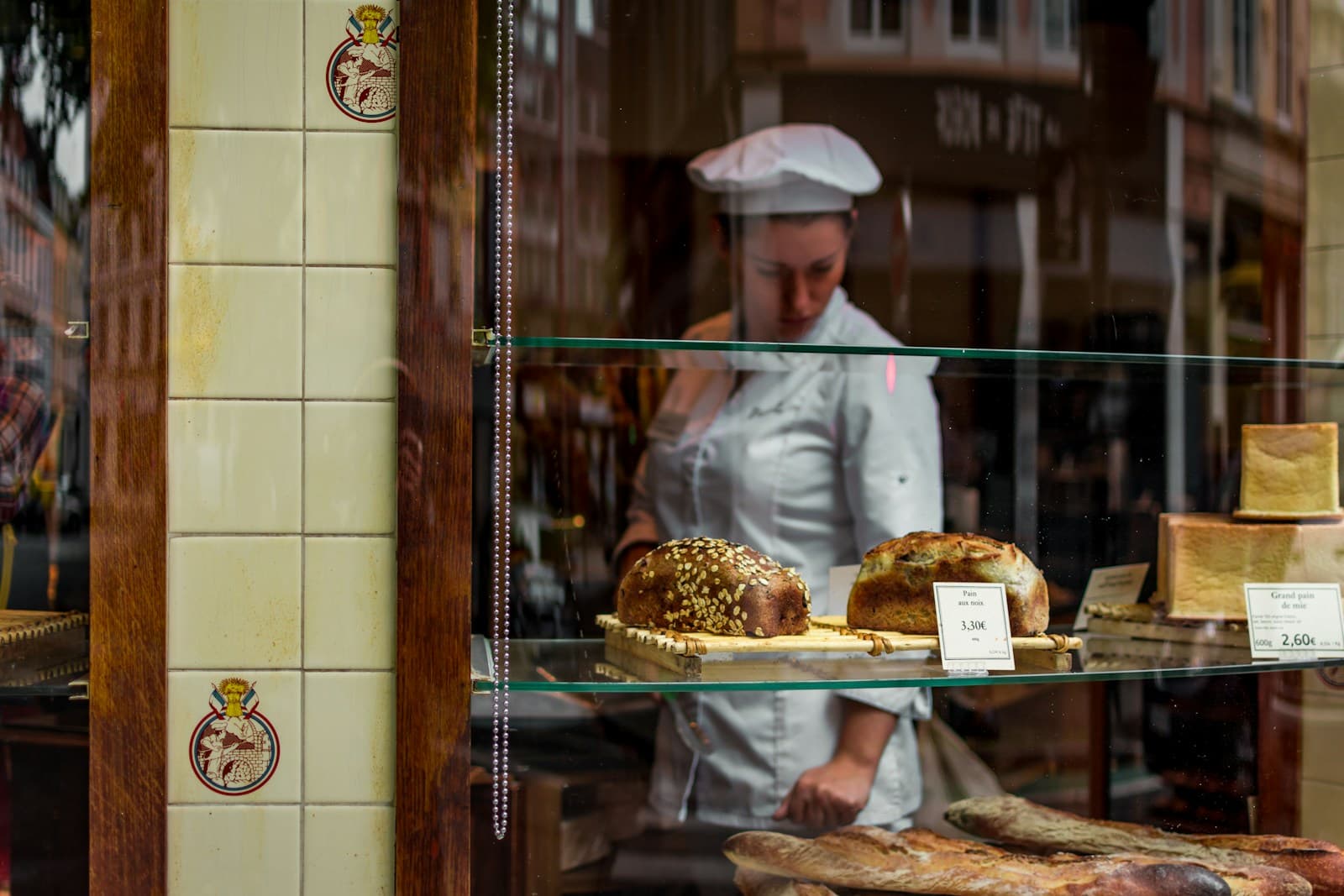 A baker setting out freshly finished breads behind a bakery counter